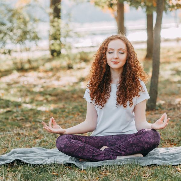 Woman meditating peacefully in a serene setting.